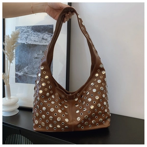 Détail d'un sac Hobo marron avec œillets métalliques argentés et rivets de style punk