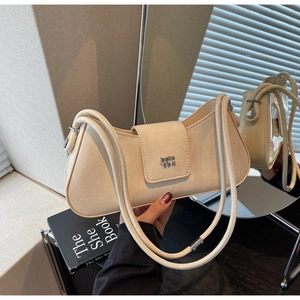 Détail macro du sac baguette crème avec boucle magnétique et texture en cuir fin