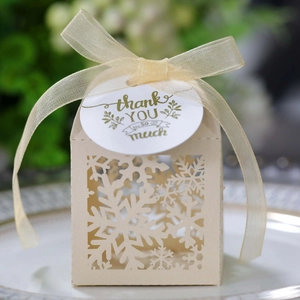 Close-up of laser-cut snowflake candy box with gold ribbon and thank you tag