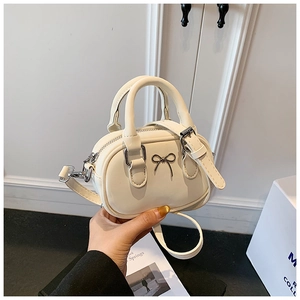 Detail of a mini cream PU leather bowling bag with silver bow buckle and top handle
