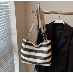Close-up of black and white striped woven tote bag featuring chain and leather straps