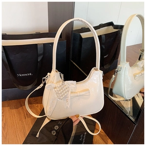 Detailansicht der cremefarbenen Leder-Tasche mit Bogen- und Perlen-Spitzenanhänger