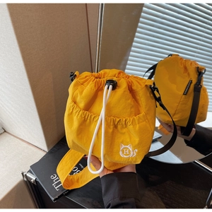 Close-up of bright yellow nylon bucket bag featuring cat embroidery and drawstring closure
