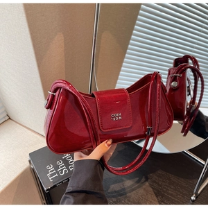 Détail du sac baguette en cuir verni rouge avec logo en métal argenté et fini brillant