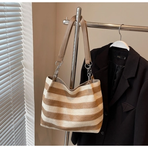 Detail of striped straw tote bag with faux leather straps and silver chain links