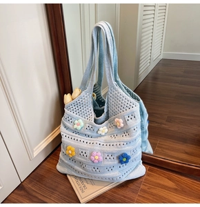 Dettaglio borsa tote in maglia azzurra con fiori all'uncinetto 3D e trama traforata