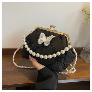 Close-up of black embroidered kiss-lock bag featuring lace butterfly and pearl straps