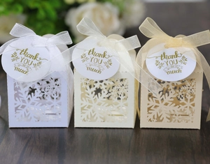 Detail of laser-cut snowflake candy boxes with silk ribbons and thank you gift tags