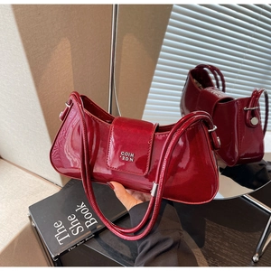 Détail du sac baguette en cuir verni bordeaux avec logo métallique et fine bandoulière