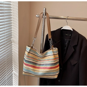 Close-up of colorful striped straw woven tote bag with brown leather handles and chain details