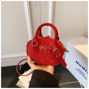 Close-up of mini red glossy bowling bag featuring a silver metal bow and top handle