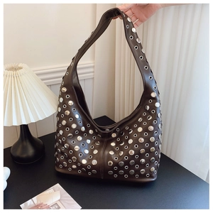 Détail d'un sac hobo marron foncé style punk avec clous et œillets en métal argenté