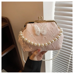 Close-up of pink frame bag with floral butterfly embroidery and pearl strap detail