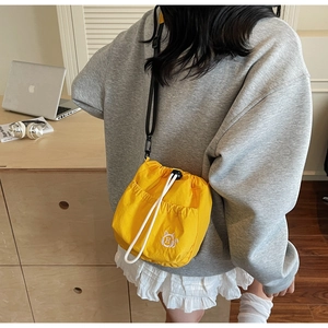 Detail view of yellow nylon bucket bag with white cat embroidery and drawstring closure