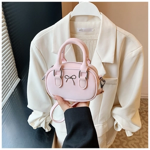 Close-up of mini pink bowling bag with metallic bow detail and top handles