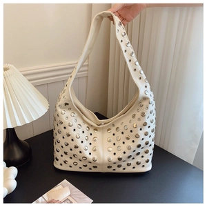Gros plan du sac hobo beige style punk avec rivets en métal et détails d'oeillets