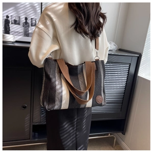 Detailed macro view of woven stripe texture and brown strap on casual tote bag