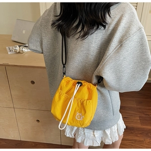 Detail of yellow nylon bucket bag with white drawstring closure and cat embroidery