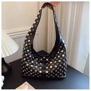 Détail macro du sac seau punk noir avec des clous métalliques argentés et œillets