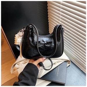 Detail der schwarzen Lackleder-Hobo-Tasche mit Faltenstruktur und Perlen-Anhänger