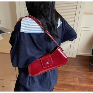 Détail du sac baguette en cuir verni bordeaux avec logo en métal argenté et bandoulière
