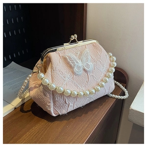 Close-up of pink pleated frame bag with lace butterfly applique and pearl strap