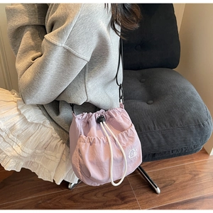 Detail of lavender drawstring bucket bag with white cat embroidery and cotton cord