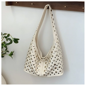 Détail du sac hobo crème orné de clous punk argentés et de motifs découpés
