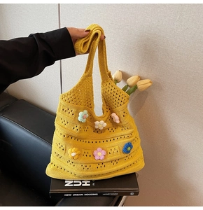 Dettaglio di borsa in maglia giallo brillante con fiori 3D all'uncinetto multicolore