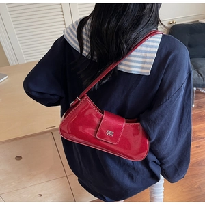 Détail du sac à bandoulière en cuir verni rouge brillant avec logo en métal argenté