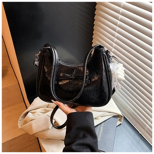 Detail der schwarzen Lackleder-Tasche mit Schleife und Anhänger aus Spitze und Perlen
