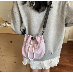 Detail of lavender bucket bag with white cat embroidery and adjustable strap on a model