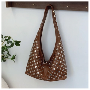 Gros plan d'un sac seau punk marron avec clous et œillets en métal argenté sur similicuir de luxe