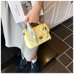 Detail of yellow quilted bag with silver twist lock and floral silk scarf handle