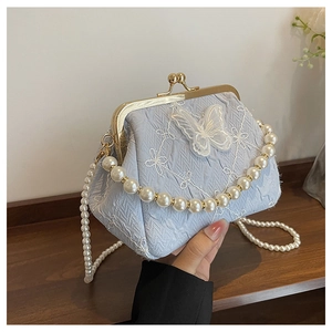 Close-up of light blue fabric handbag with butterfly embroidery and pearl chain