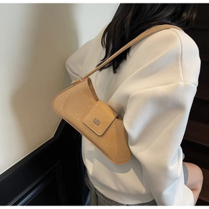 Détail d'un sac baguette en cuir verni beige brillant avec logo métallique chic