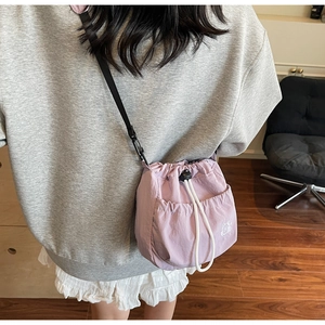 Side view of lavender purple drawstring bucket bag with embroidered logo and adjustable strap