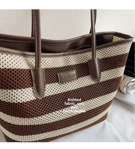 Nahaufnahme der weichen Strickstruktur und des braunen Leder-Markenetiketts der Tasche