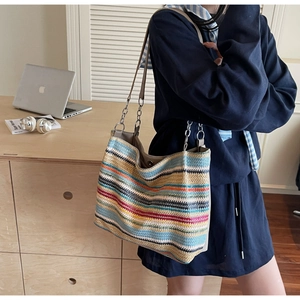 Detail of colorful rainbow woven tote bag featuring leather handles and metal chain straps