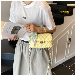 Detail of light yellow quilted crossbody bag with silver clasp and blue floral silk scarf