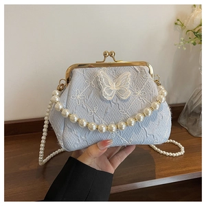 Detailed view of light blue embroidered handbag with lace butterflies and pearl chain