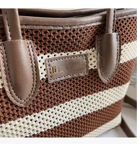 Detail der gestreiften gewebten Tasche mit braunem Lederlogo und strukturierter Textur