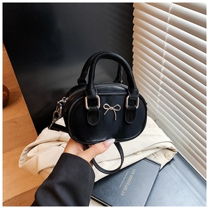 Detail of a mini black leather bowling bag with silver bow hardware and top handles