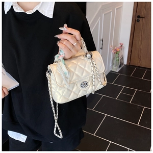 Close-up of beige quilted crossbody bag with silver chain and silk scarf handle detail