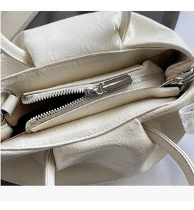 Detailed close-up of smooth silver zipper on a cream pleated crossbody bag for women