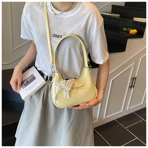Detail einer hellgelben gerafften Handtasche mit Perlschleife und feiner Spitze