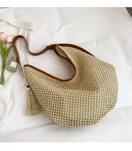 Detail of woven straw tote bag with brown leather strap and decorative fringe tassel