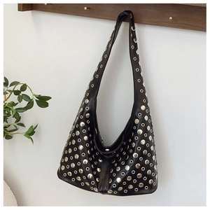 Détail d'un sac hobo punk noir avec rivets argentés suspendu à un portant en bois