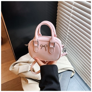 Detail of a mini pale pink bowling bag with metal bow and detachable shoulder strap