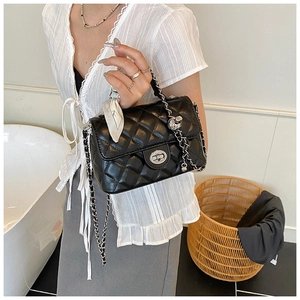 Detail of black quilted crossbody bag with silver chain strap and decorative silk scarf